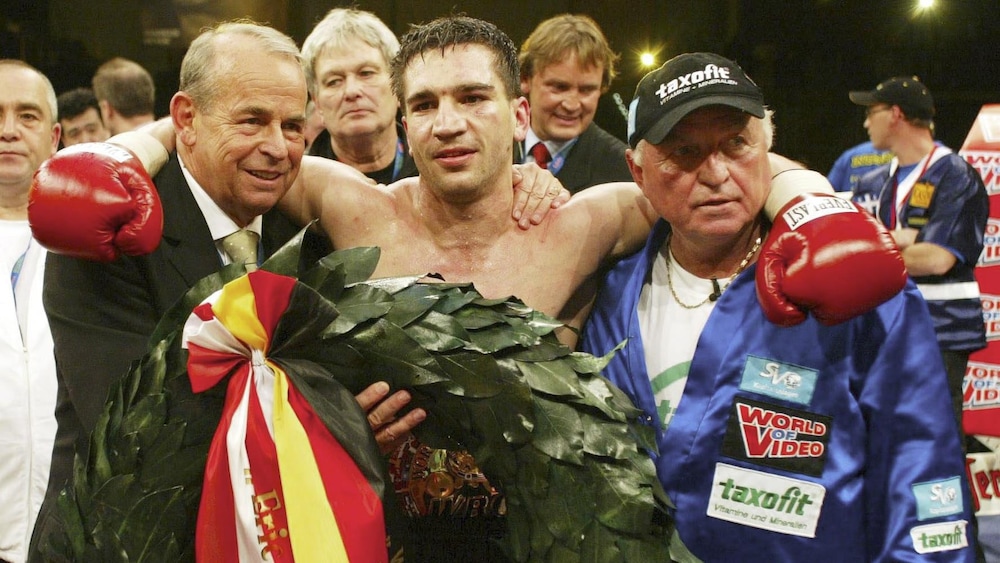 Le promoteur Wifried Sauerland (à gauche) et l'entraîneur Ulrich Wegner (à droite) entourent Markus Beyer après sa victoire le 5 avril 2003.