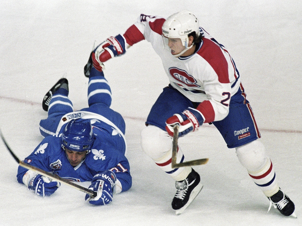 Valeri Kamenski, des Nordiques, tombe sur la glace en tentant de bloquer Éric Desjardins, du Canadien.