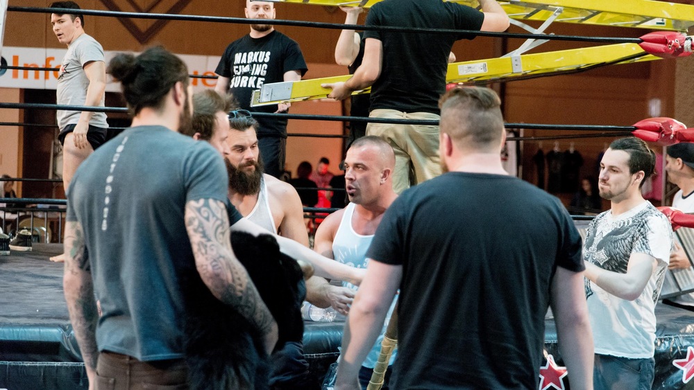 Premières discussions aux abords du ring pour les têtes d'affiche en vue du combat principal. Au centre, le champion de la NSPW Marko Estrada.