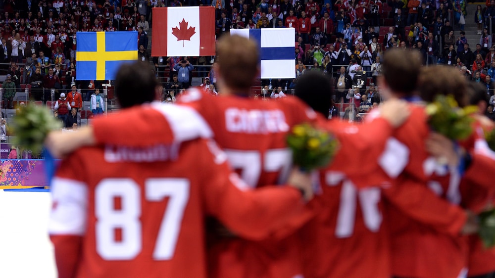 es joueurs du Canada regardent les drapeaux des équipes médaillées être hissés au plafond du Bolchoï Ice Dome après la finale.