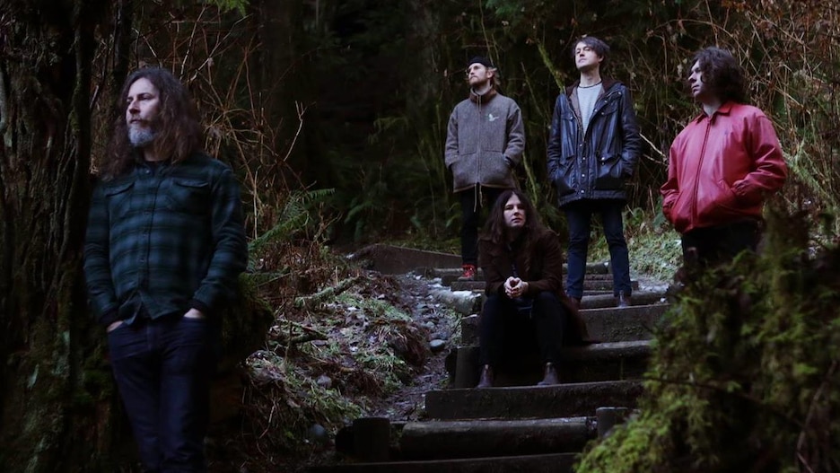 Vancouver psych rock band Black Mountain stands in a forest.