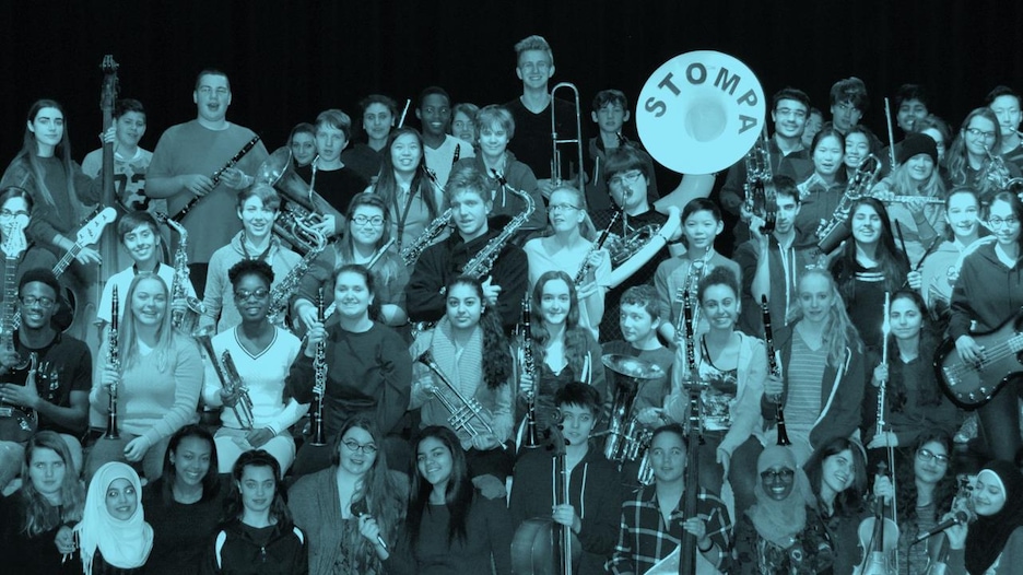 Hillcrest High School's music class is shown standing together with their instruments. 