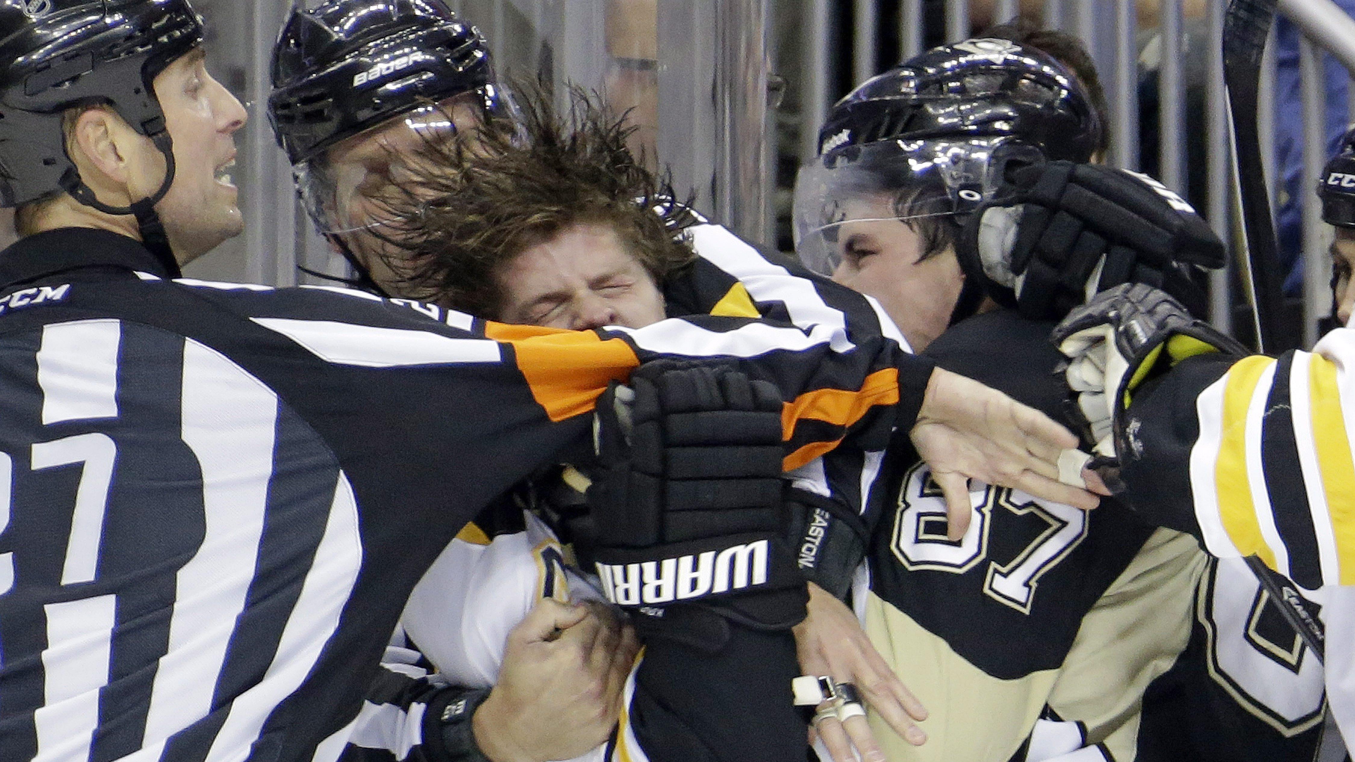 Eric Furlatt (gauche) tente de séparer Sidney Crosby (87) et Torey Krug, en 2013.