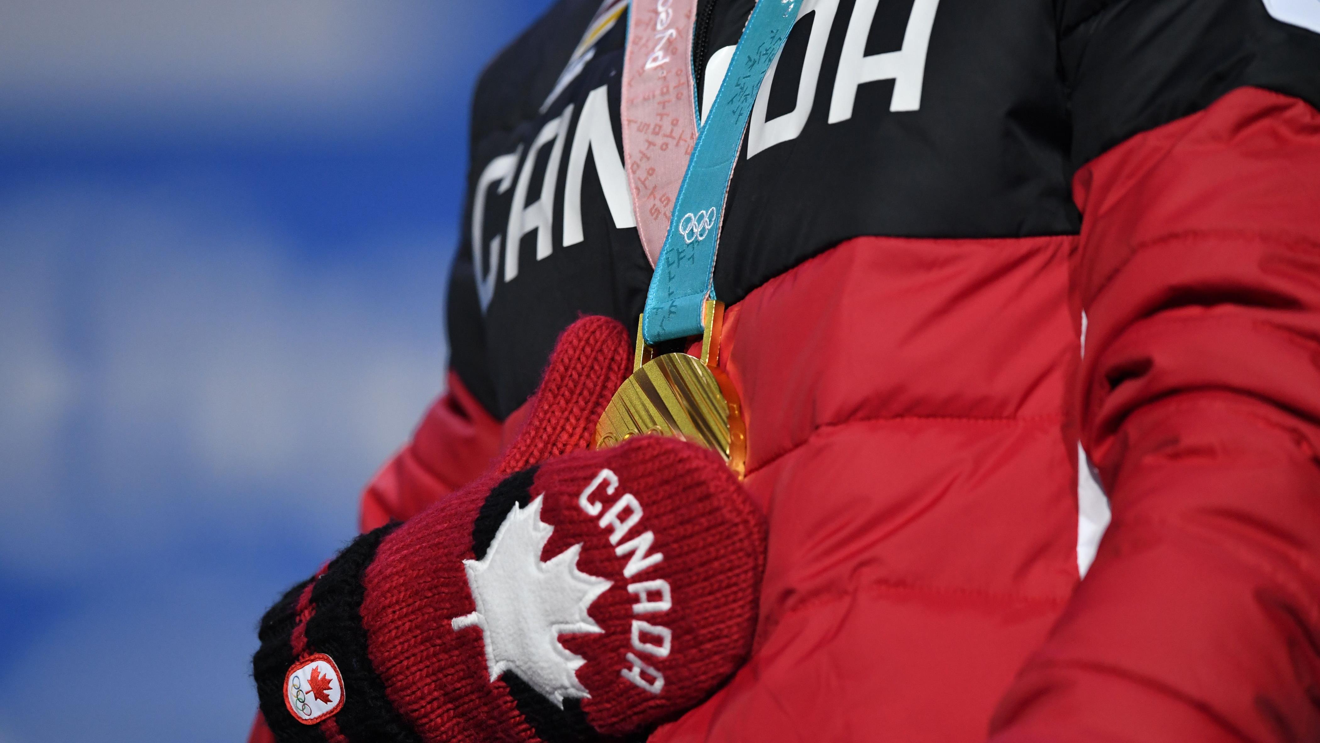 Mikaël Kingsbury pose sa main sur sa médaille d'or.