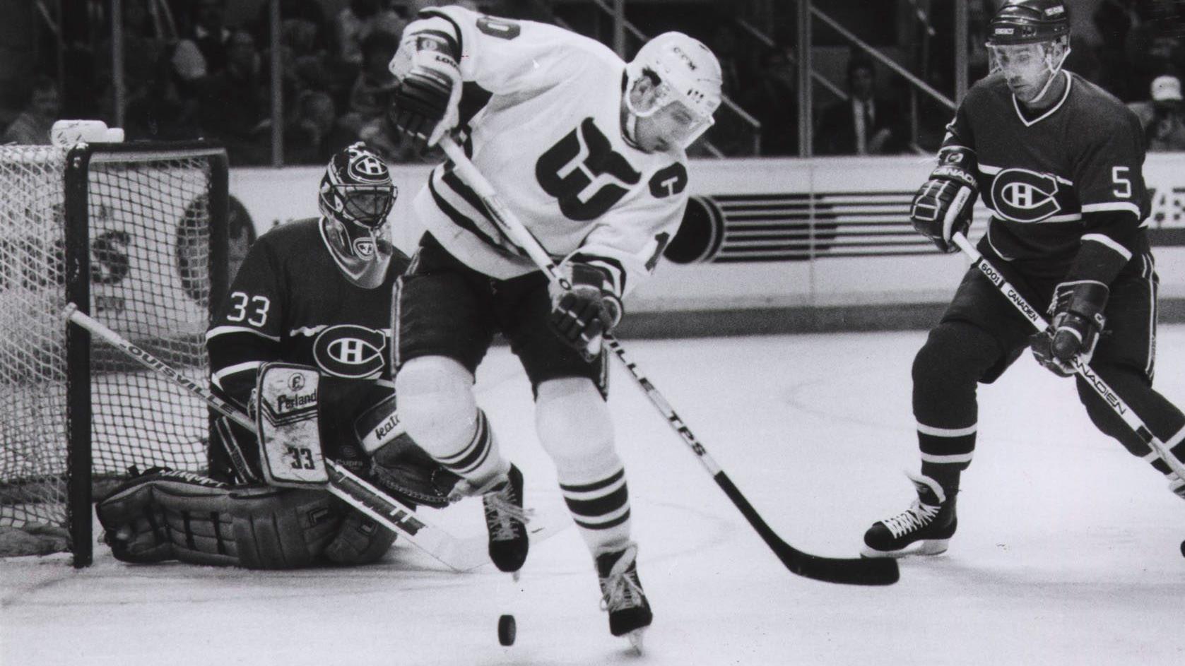 Patrick Roy observe attentivement la rondelle que tente de contrôler Ron Francis, des Whalers de Hartford, sous le regard du défenseur Rick Green, en 1989.