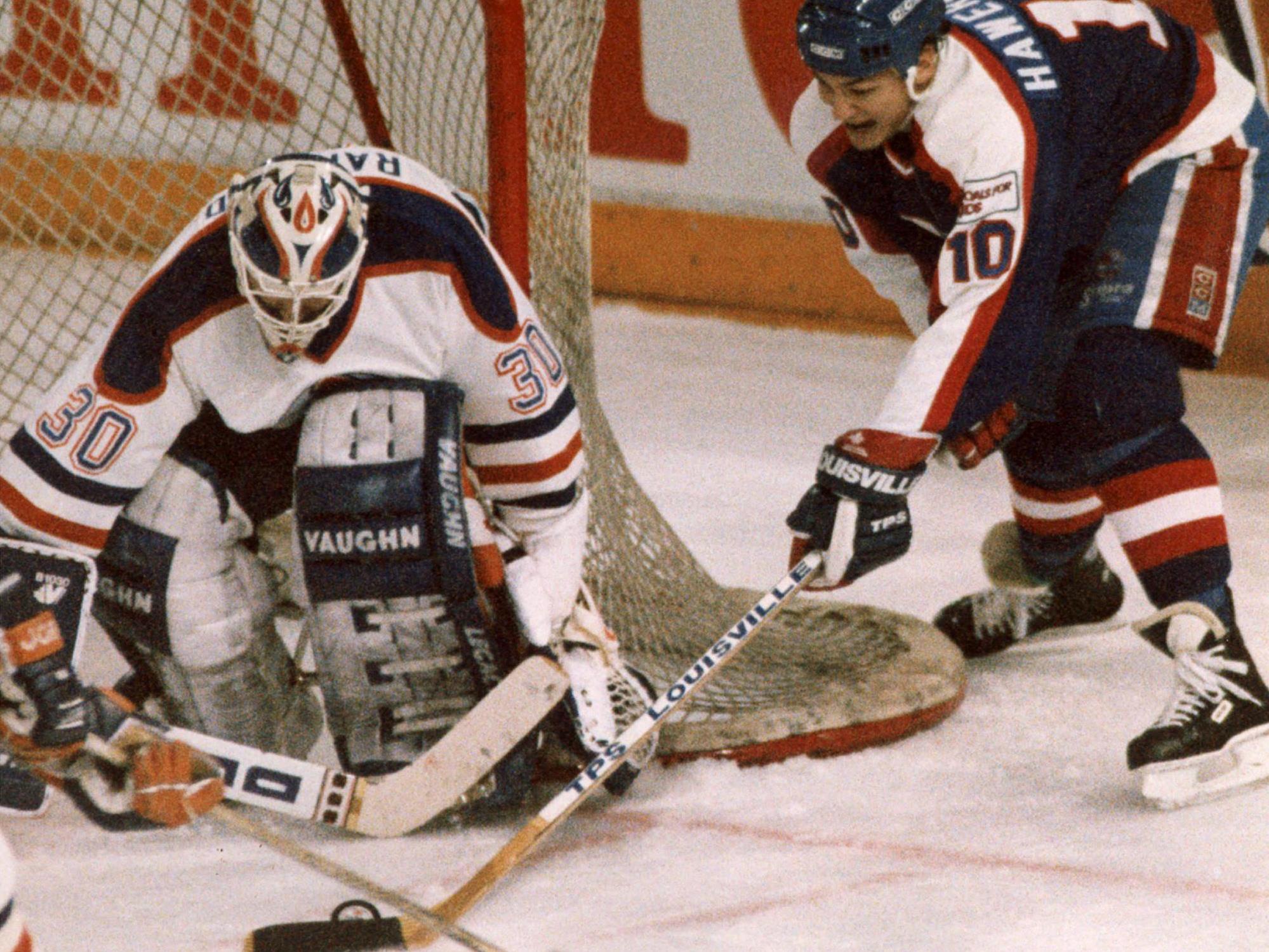 Dale Hawerchuk tente de surprendre le gardien Bill Ranford de l’arrière du filet.