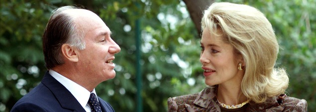 Le prince parle à sa femme, qui l'écoute en souriant. Le couple est entouré d'arbres.