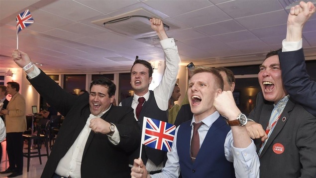Quatre jeunes hommes lèvent le poing et agitent des drapeaux britanniques