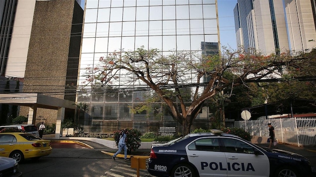 Une voiture de police est stationnée devant l'immeuble.