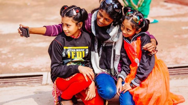Des filles se photographient en selfie dans une rue de New Delhi