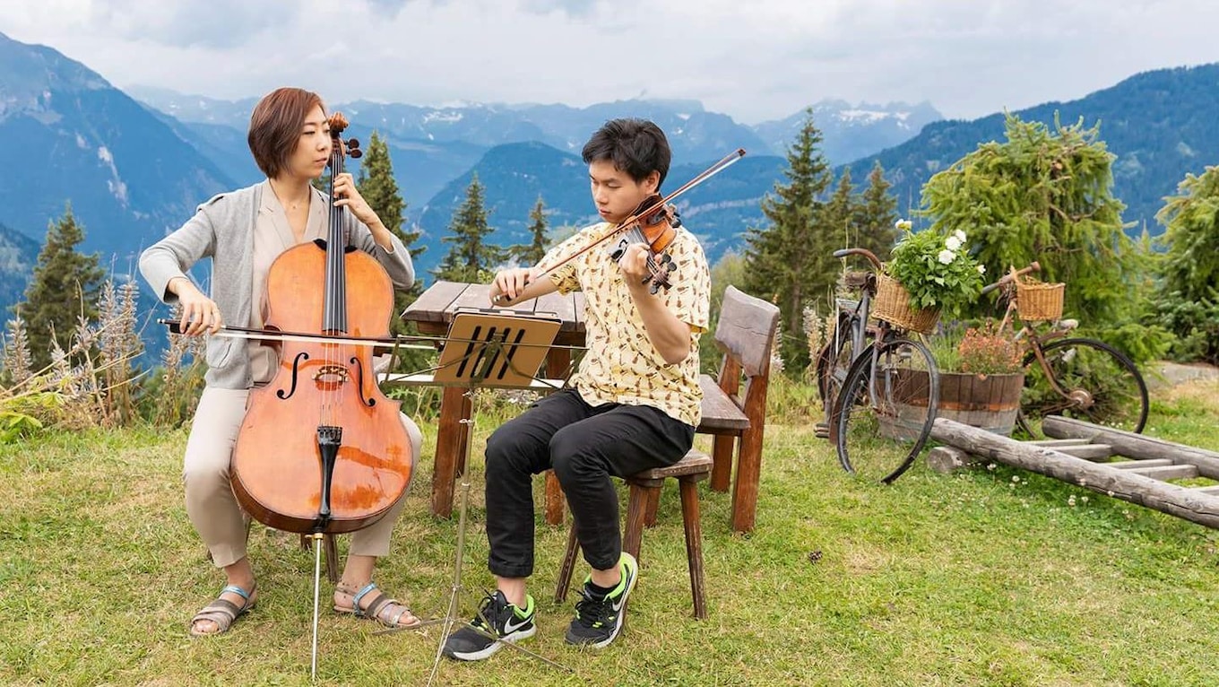 Cellist Christine J. Lee and violinist Timothy Chooi perform atop a Swiss Mountain while taking part in the 2018 Verbier Festival Academy.