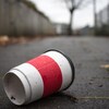 Une tasse à café jetable gît au sol. 