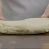 Un bloc de pâte est posé sur une planche à découper. 