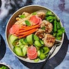 Un bol bien garni avec des boulettes de porc, du concombre, des carottes, des radis, des herbes fraîches et des nouilles.