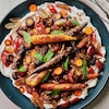 Sur une grande assiette de service, des carottes rôties au miel, raisins et dukka réparties sur du labneh.
