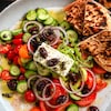 Une salade grecque composée d'olives, de tomates, de concombres et de poivrons, garnie de feta, d'olives et de câpres.