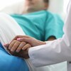 Un docteur tient la main d'un patient dans un lit. 