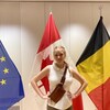 Capri sourit devant les drapeaux de l'Union européenne, du Canada et de la Belgique à l'ambassade canadienne à Bruxelles.