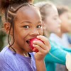 Une enfant mange une pomme.