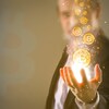 Des symboles représentant des bitcoins tombent dans la main d'un homme.