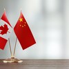 Deux drapeaux côte à côte : celui de la Chine et celui du Canada.
