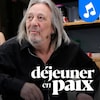 Serge Fiori portant un micro-casque, assis dans une chaise, et le logo de l'émission Déjeuner en paix.