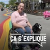 Anaïs Sabourin se déplace en fauteuil roulant en compagnie de sa chienne d'assistance, Mika. Ils sont sur la rue Ste-Catherine. Des arc-en-ciel ont été dessinés sur la rue.