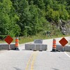 Le chemin est bloqué par des blocs de béton, des panneaux, des cônes orange et un signe « entrée interdite ».