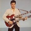 Elvis Presley tient une guitare double. 