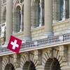 Un drapeau suisse devant un bâtiment.