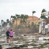 Des personnes marchent le long de la plage en regardant les biens endommagés par l'ouragan Ian à Bonita Springs.