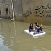 Deux jeunes filles naviguent sur un matelas dans une rue.