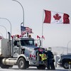 Des personnes déplacent un camion sur les lieux d'une manifestation aux environs du poste frontalier de Coutts, dans le sud de l'Alberta, le 2 février 2022.