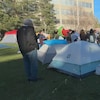 Des tentes et des manifestants occupent un terrain de l'Université de l'Alberta. À l'avant-plan, une banderole indique, en anglais : « Bienvenue à l'Université du peuple pour la Palestine », à Edmonton, le jeudi 9 mai 2024.