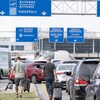 Deux passagers traînent leur valise au milieu des embouteillages à l'entrée de l'aéroport de Montréal.