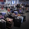 Des passagers attendent en ligne à l'aéroport Pearson près d'une vingtaine de valises.
