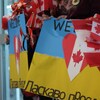 Une foule dans un aéroport accueille des réfugiés ukrainiens. Ils ont des drapeaux canadiens et ukrainiens dans les mains. 