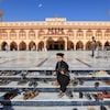Un garçon marche parmi les chaussures laissées par les fidèles devant une mosquée.