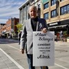 Un candidat se tient debout avec sa pancarte électorale