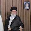 Ali Khamenei pose aux côté du drapeau iranien et d'un portrait de l'ayatollah Rouhollah Khomeini.