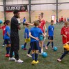 Alphonso Davies sur un terrain de soccer avec des enfants et des entraîneurs. 