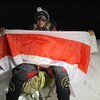 Liliya Ianovskaia tenant un drapeau national biélorusse au sommet du K2, au Pakistan.