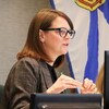 Amanda McDougall de profil, assise, en train de parler, devant un écran d'ordinateur et près d'un drapeau de la Nouvelle-Écosse suspendu à un mur.