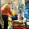 Un homme couché sur une civière dans une ambulance avec deux ambulanciers debout près de lui.