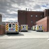Plusieurs ambulances sont garer devant un hôpital.