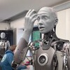 Un robot humanoïde regarde sa main avec stupéfaction. 
