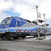 Un train de banlieue d'Exo traverse un passage à niveau, en hiver.