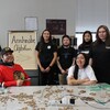 Des jeunes posent pour la photo dans une salle de classe avec des artefacts étalés sur la table.