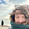 Annette Paiement est sur la plage Nicket. Son foulard est remonté vers sa bouche, ses cheveux au vent sont retenus par une paire de lunettes. Elle prend un selfie. Derrière elle, on aperçoit les vagues du lac Érié et une silhouette de dos.