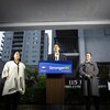 Le premier ministre David Eby fait une annonce sur un podium devant un immeuble résidentiel.